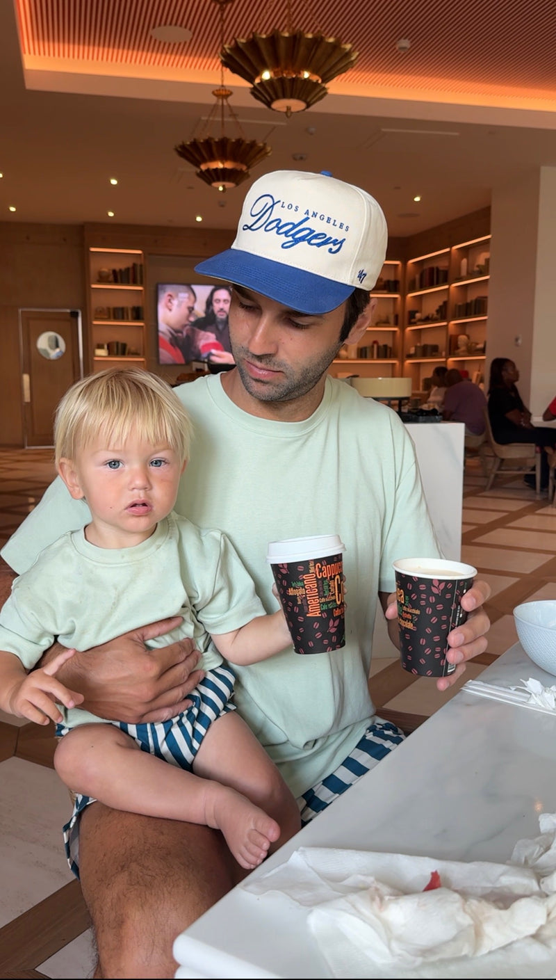 Man and toddler wearing matching sage Classic T-shirts at a café