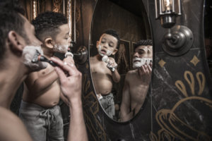 Son watching and imitating father shaving