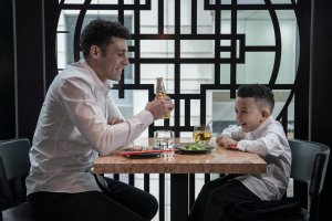 Father and son having dinner in a restaurant wearing matching MANCUB white shirts